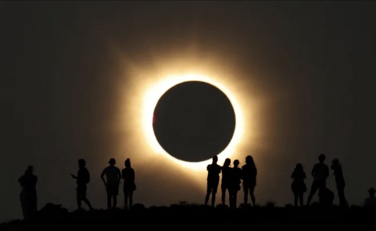 People gathered beneath the glowing corona of a total solar eclipse